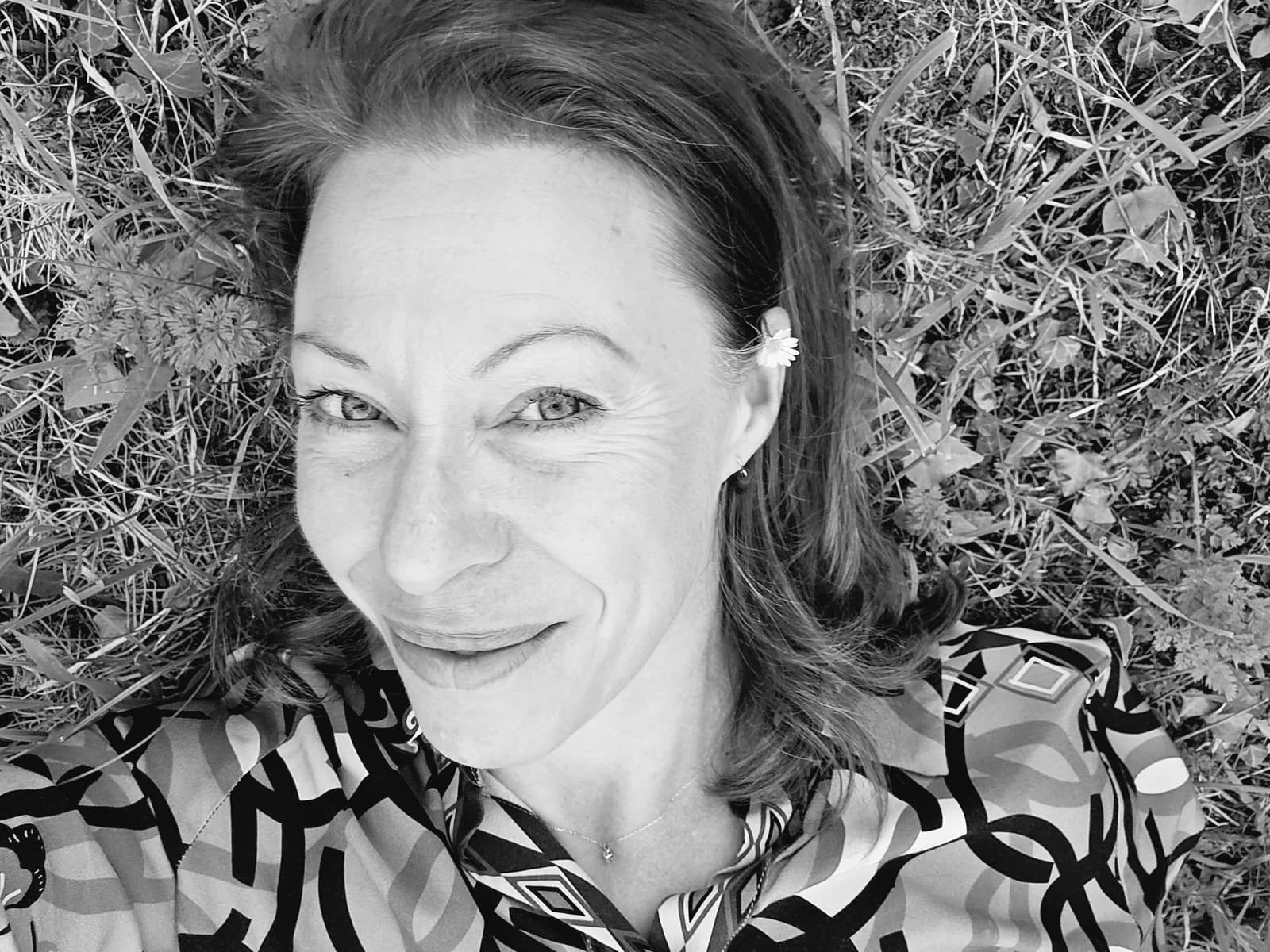 Portrait en noir et blanc de Valérie, allongée dans l’herbe